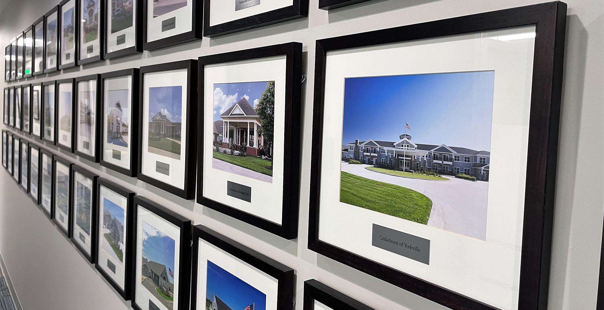 A wall of framed photos representing completed development projects